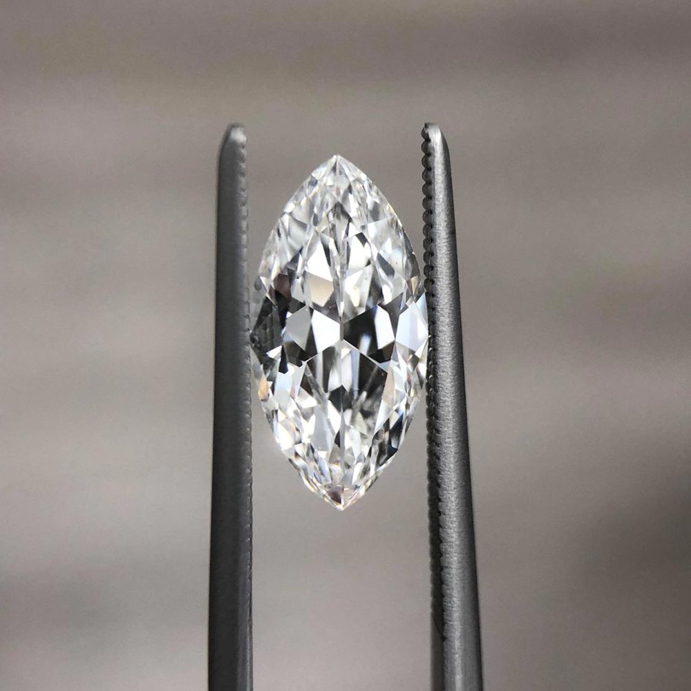 Loose white marquise diamond held in a pair of tweezers